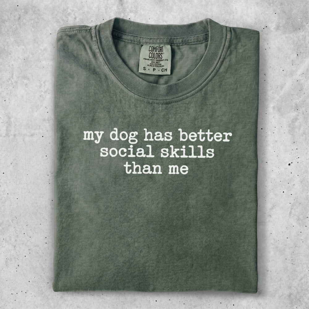 Green t-shirt with white text that reads "my dog has better social skills than me."