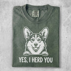 Green t-shirt with a drawing of a happy corgi and the text "YES, I HERD YOU".