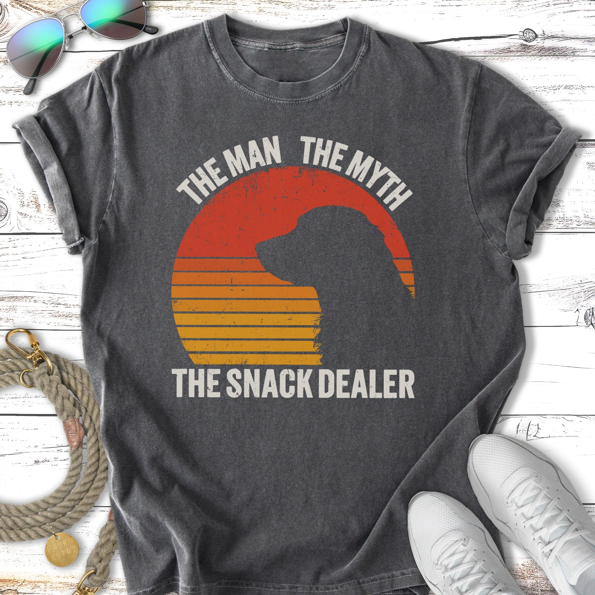 Dark t-shirt with text "THE MAN THE MYTH THE SNACK DEALER" and a sunset silhouette.
