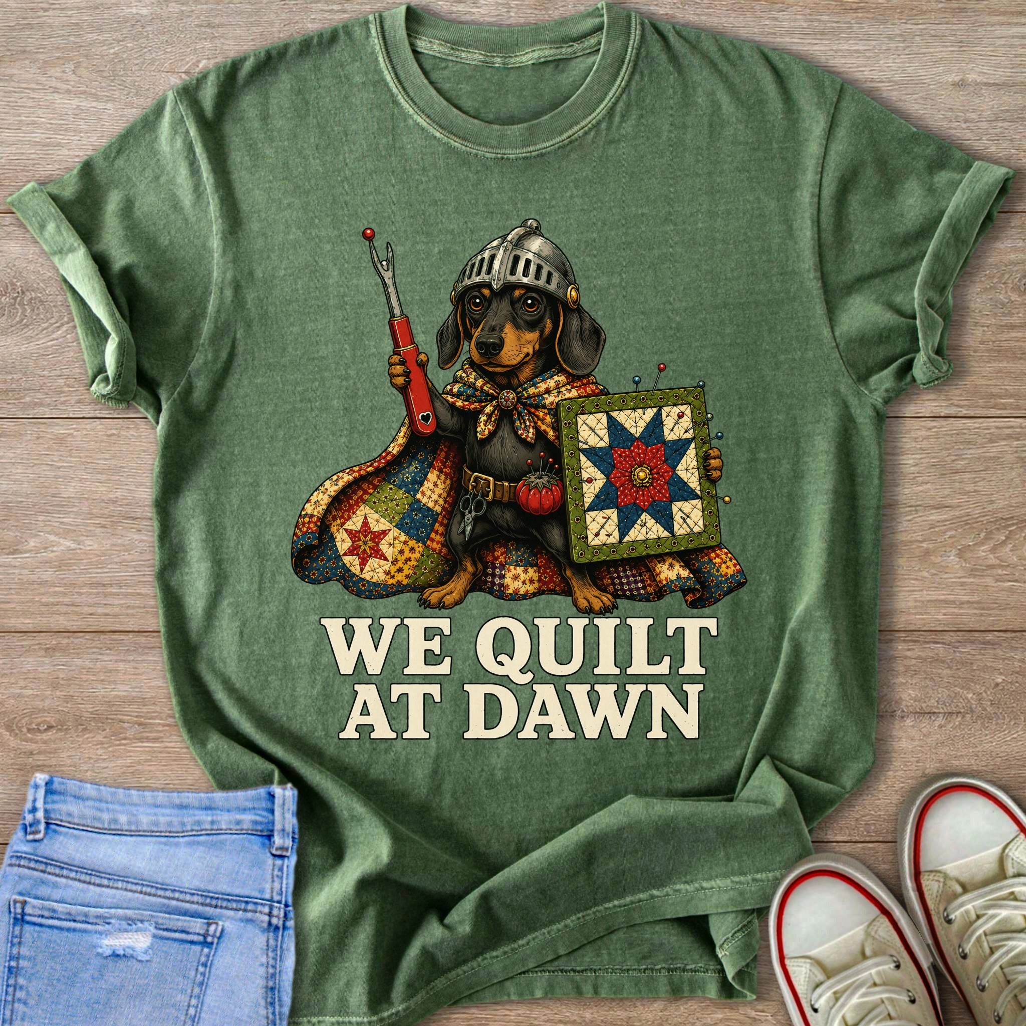 Dachshund in armor holding quilt and sewing tools, text "WE QUILT AT DAWN"