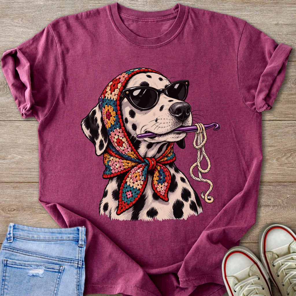 Dalmatian dog wearing sunglasses and crochet bandana holds crochet hook with yarn.