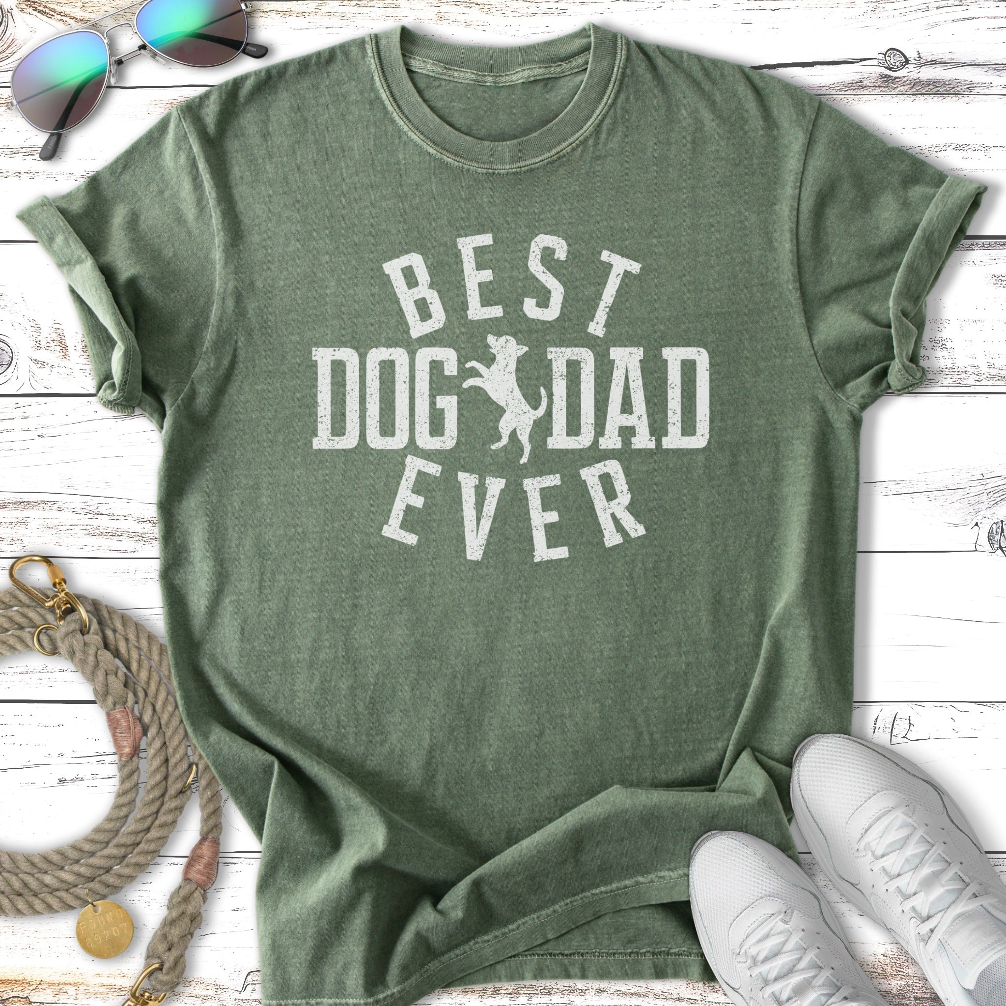 Green t-shirt with "BEST DOG DAD EVER" text, sunglasses, and sneakers.