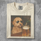 Goldendoodle wearing sunglasses sits at a table with a beer.
