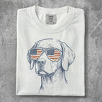 White t-shirt with patriotic dog wearing American flag sunglasses.