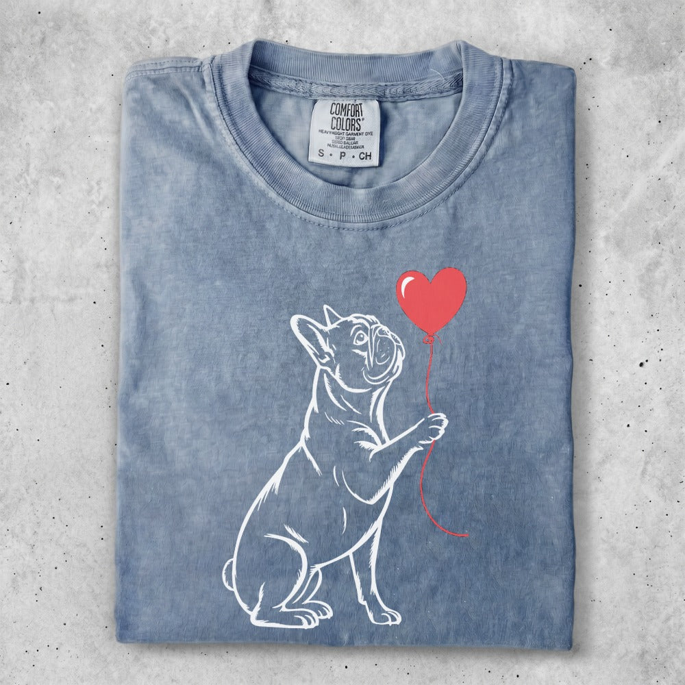 French bulldog with a red heart balloon against a faded blue t-shirt.