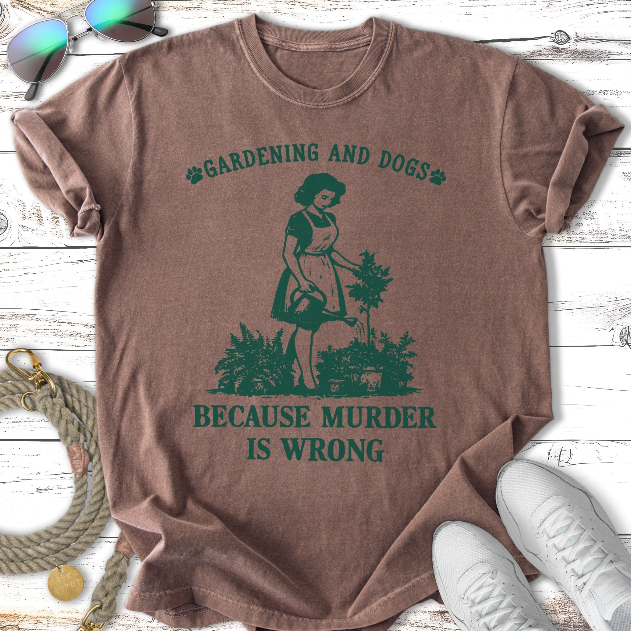 Green t-shirt with illustration of a woman gardening and text "GARDENING AND DOGS BECAUSE MURDER IS WRONG".