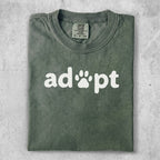Olive green t-shirt with white "adopt" text and paw print.