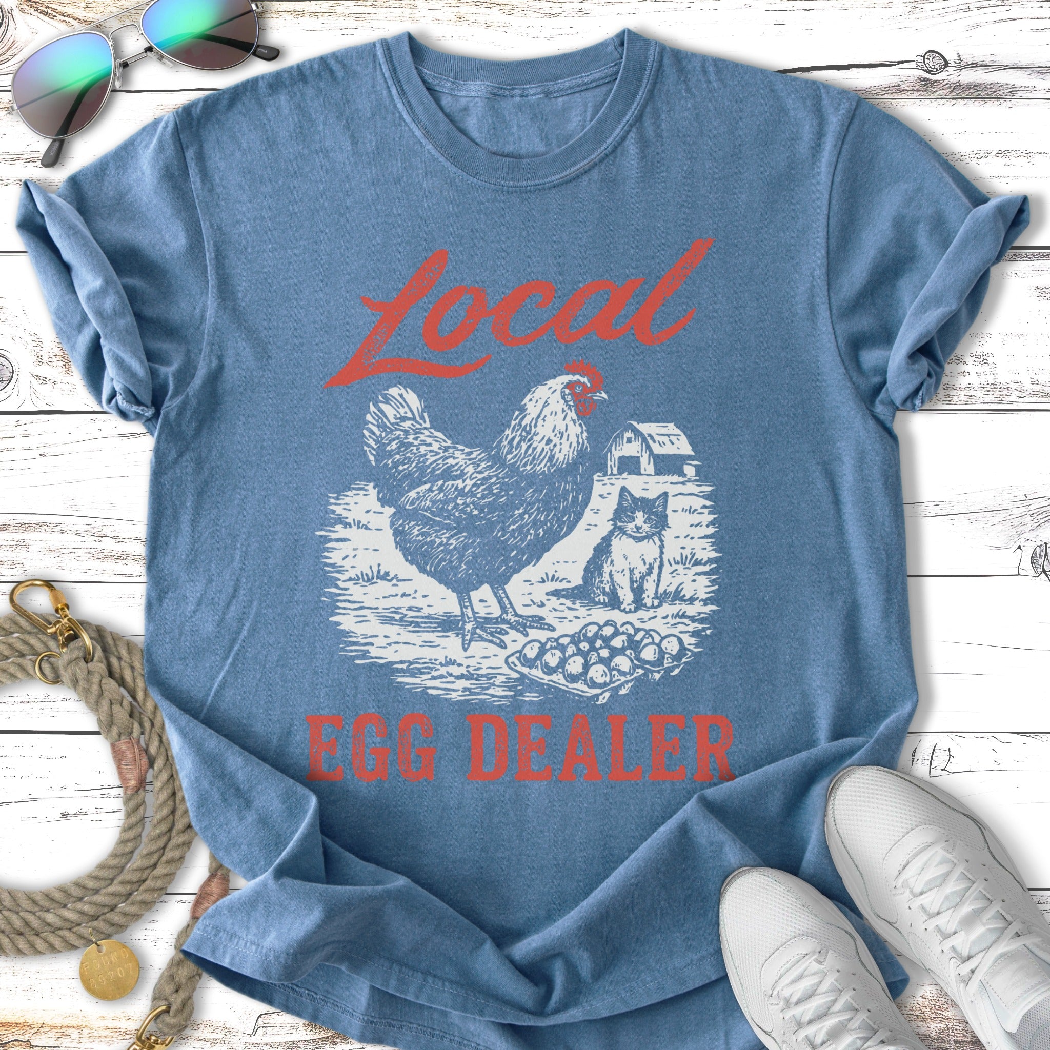 T-shirt graphic with chicken, cat, barn, and "Local Egg Dealer" text.