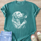 Green t-shirt with a white line drawing of a dog blowing on a dandelion.