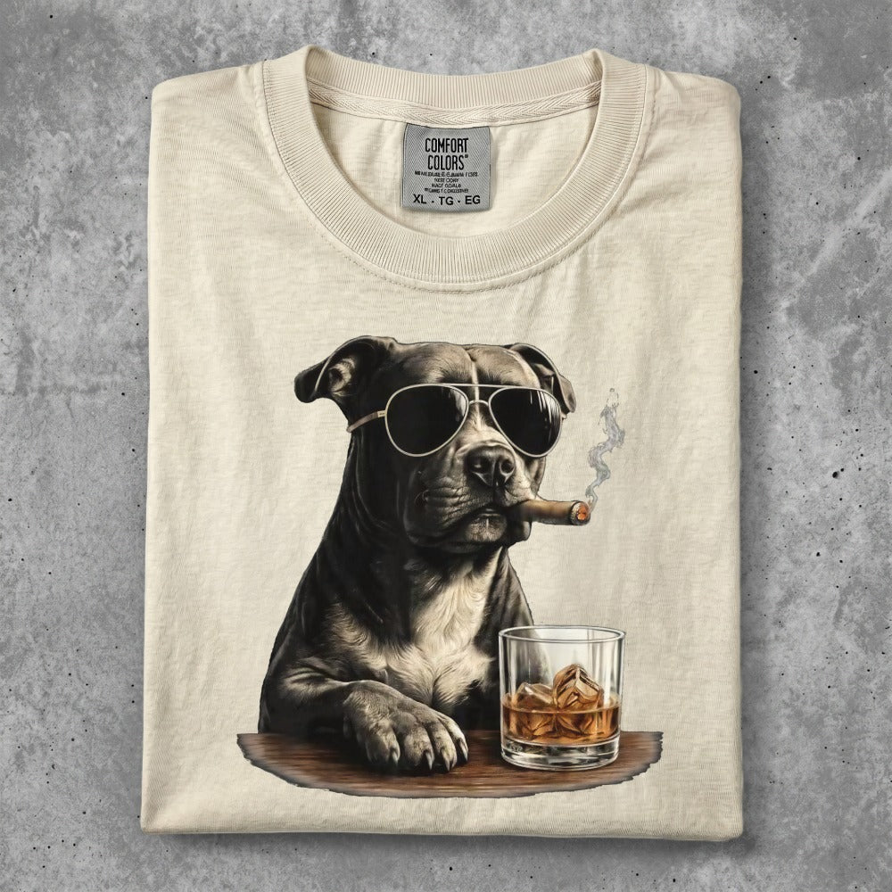 Dog wearing sunglasses smokes cigar next to whiskey and ice.