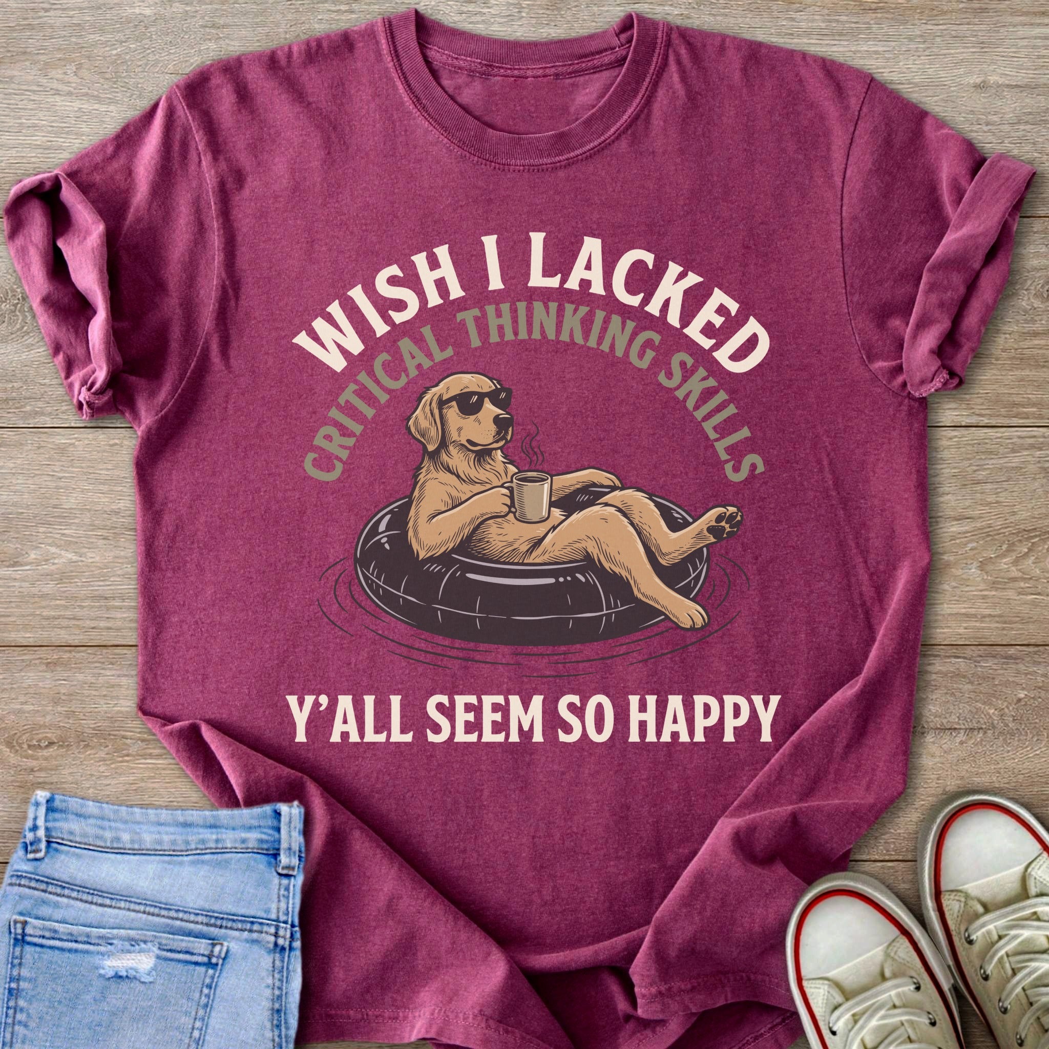 T-shirt with a dog in a float, wearing sunglasses, holding a mug. Text says "Wish I lacked critical thinking skills. Y'all seem so happy."