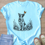 Line drawing of a German Shepherd dog with a butterfly on its nose on a light blue t-shirt.