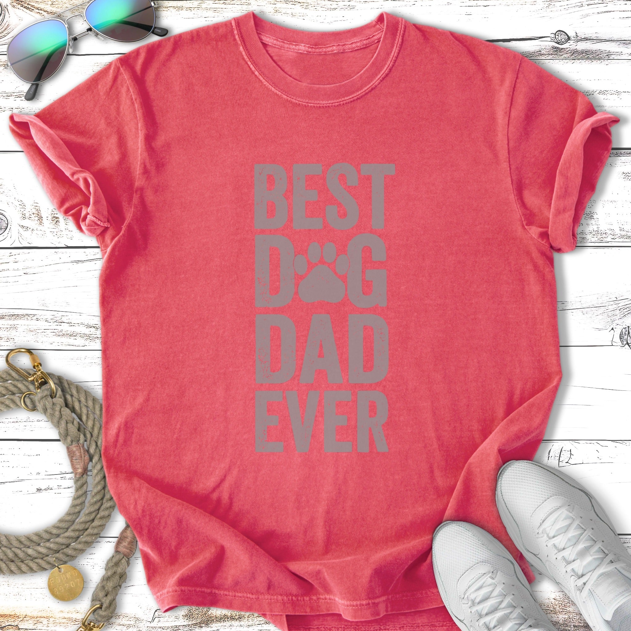 Red t-shirt with "BEST DOG DAD EVER" graphic, sunglasses, leash, and sneakers.