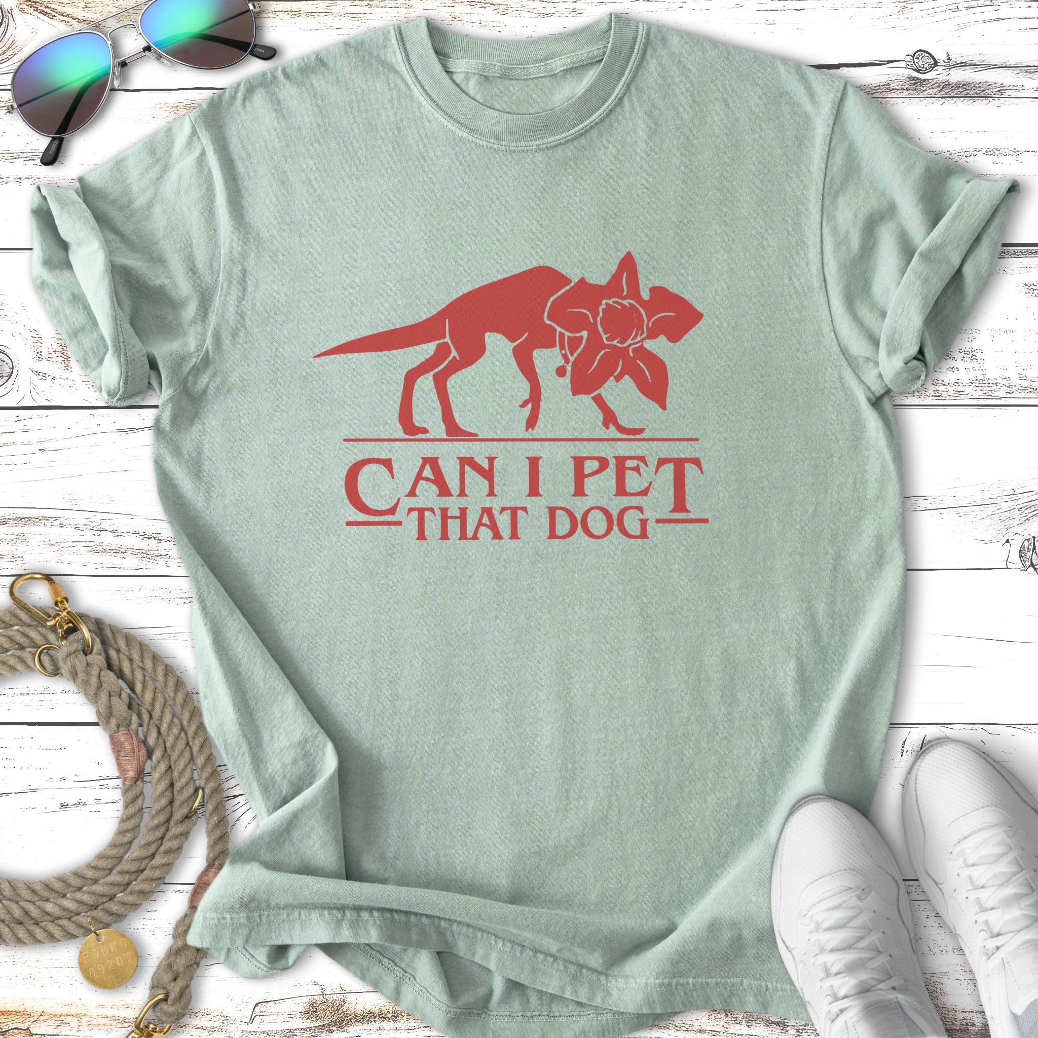 Light green t-shirt with red dinosaur and flower graphic, saying "Can I Pet That Dog".