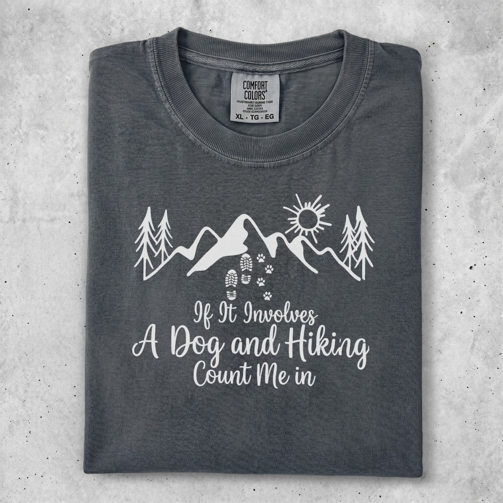 Dark grey t-shirt with mountains, trees, sun, and "If It Involves A Dog and Hiking Count Me in".