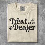 Cream t-shirt with "Treat Dealer" and paw print graphics.