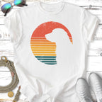 Silhouette of a dog inside a retro sunset circle graphic on a white t-shirt.