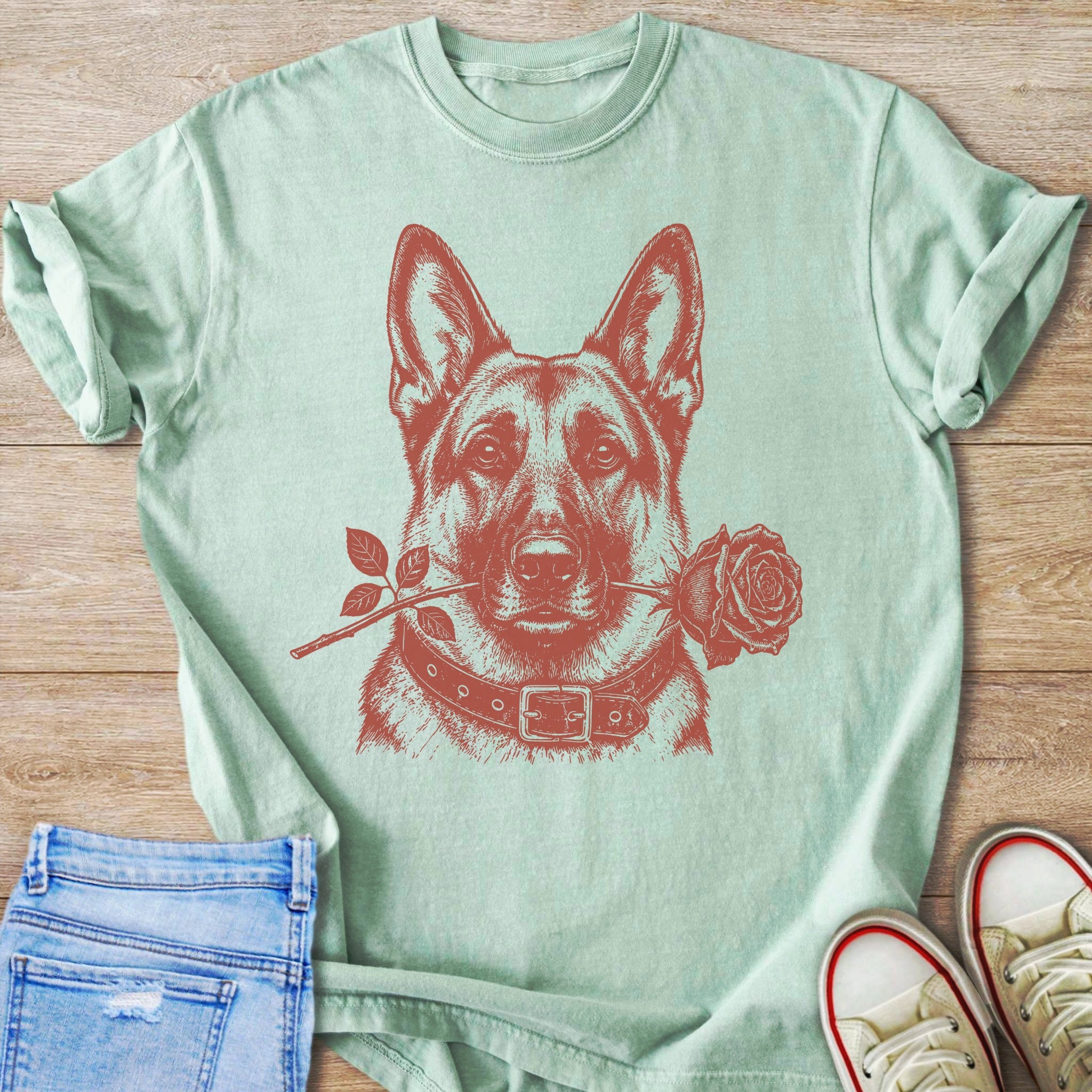 German Shepherd with a rose in its mouth on a pale green t-shirt.
