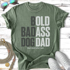 Distressed green t-shirt with "BOLD BADASS DOG DAD that's just who I am!" graphic.