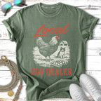 Green t-shirt with "Local Egg Dealer" text and chicken and cat illustration.
