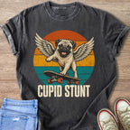 Pug with wings on skateboard, "CUPID STUNT" text, vintage sunset background.