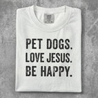 White t-shirt with black text "PET DOGS. LOVE JESUS. BE HAPPY."