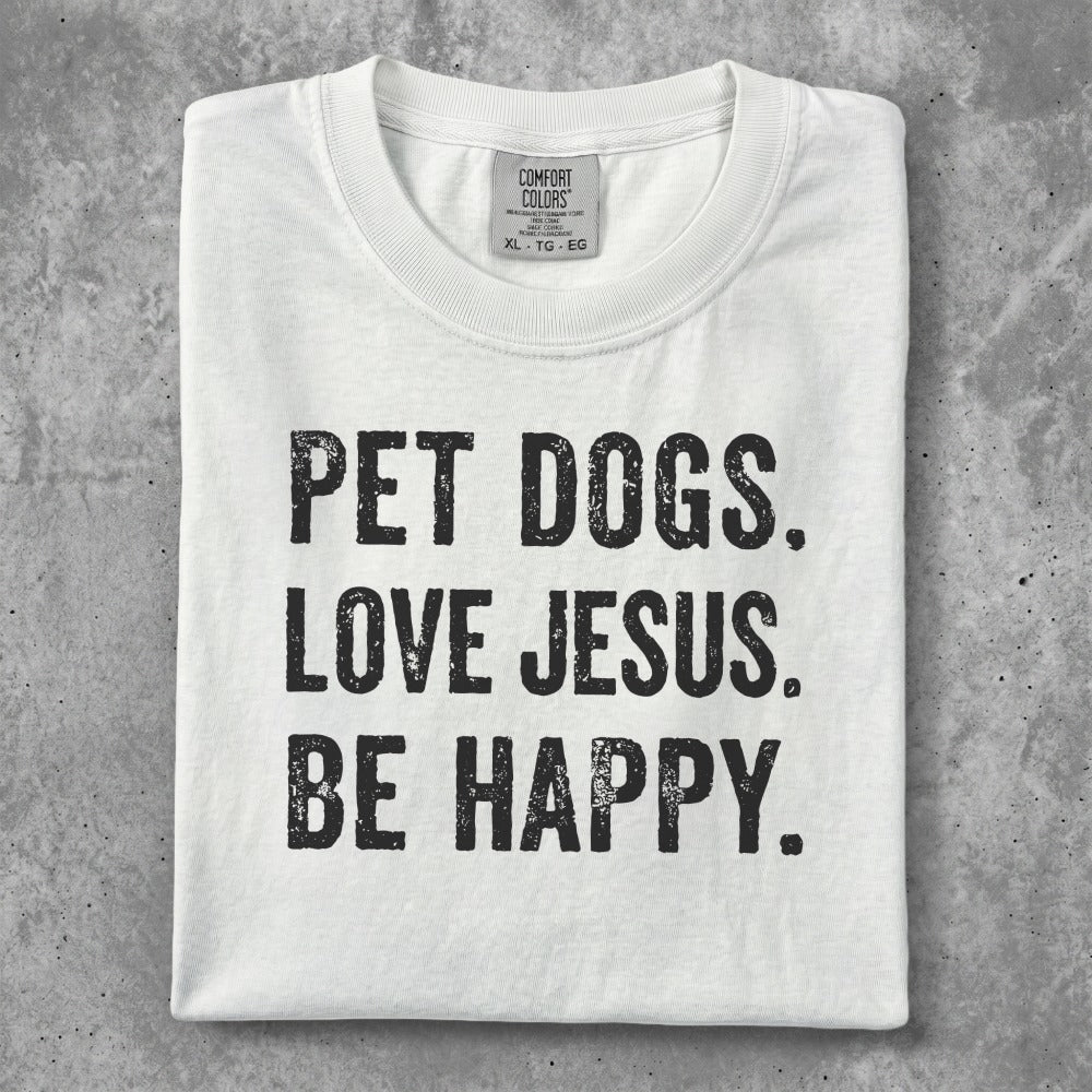 White t-shirt with black text "PET DOGS. LOVE JESUS. BE HAPPY."
