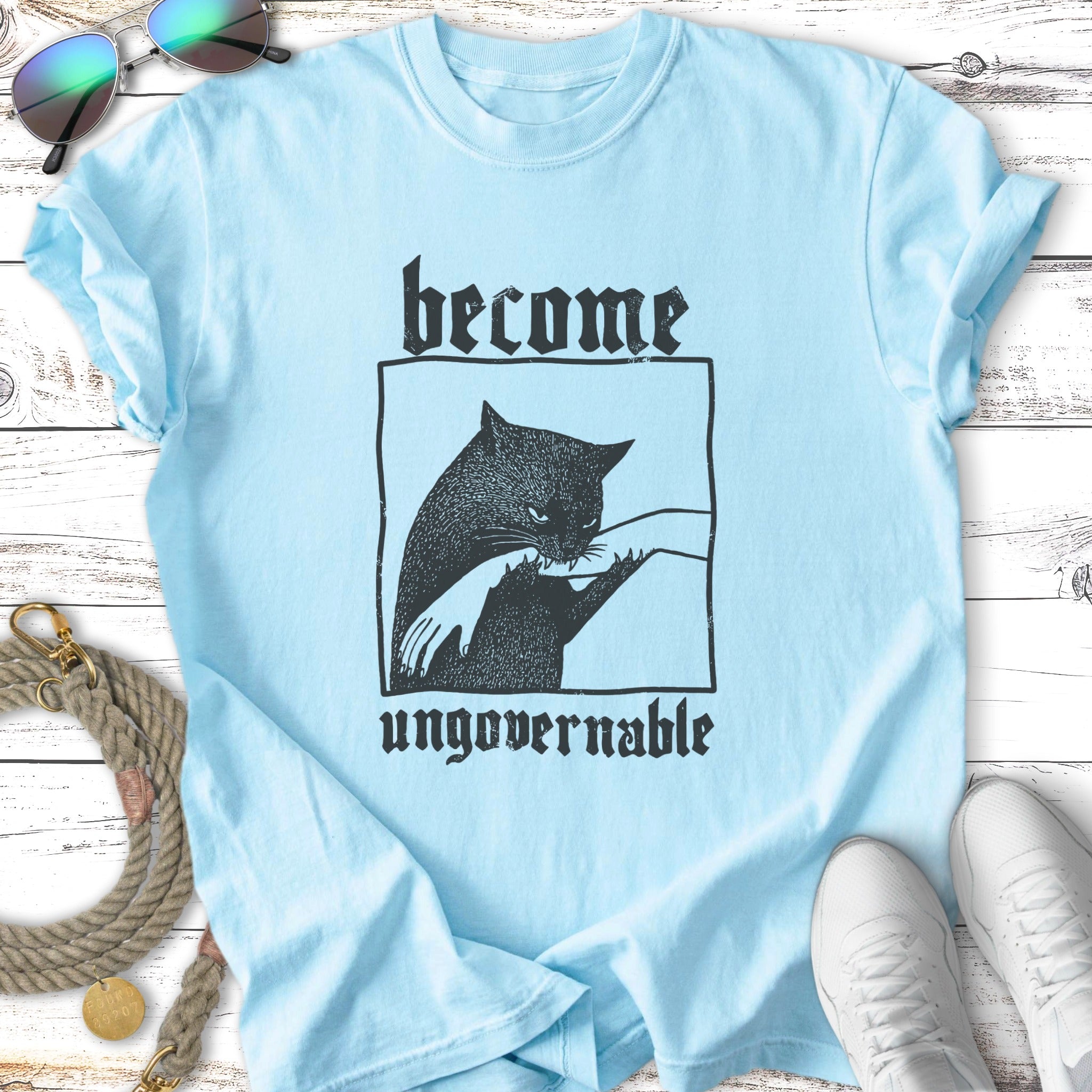 Light blue t-shirt with black cat illustration and text "become ungovernable".
