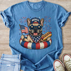 French bulldog in patriotic bandana, sunglasses, and hat on float holding flag and hot dog.