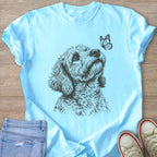 Light blue t-shirt with sketched poodle and butterfly graphic.