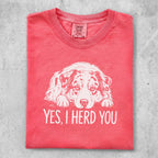 Coral t-shirt with a white line drawing of a dog and the text "YES, I HERD YOU".