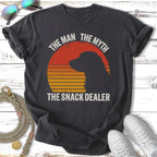 Black t-shirt with sunset graphic, dog silhouette, and text "The Man The Myth The Snack Dealer".