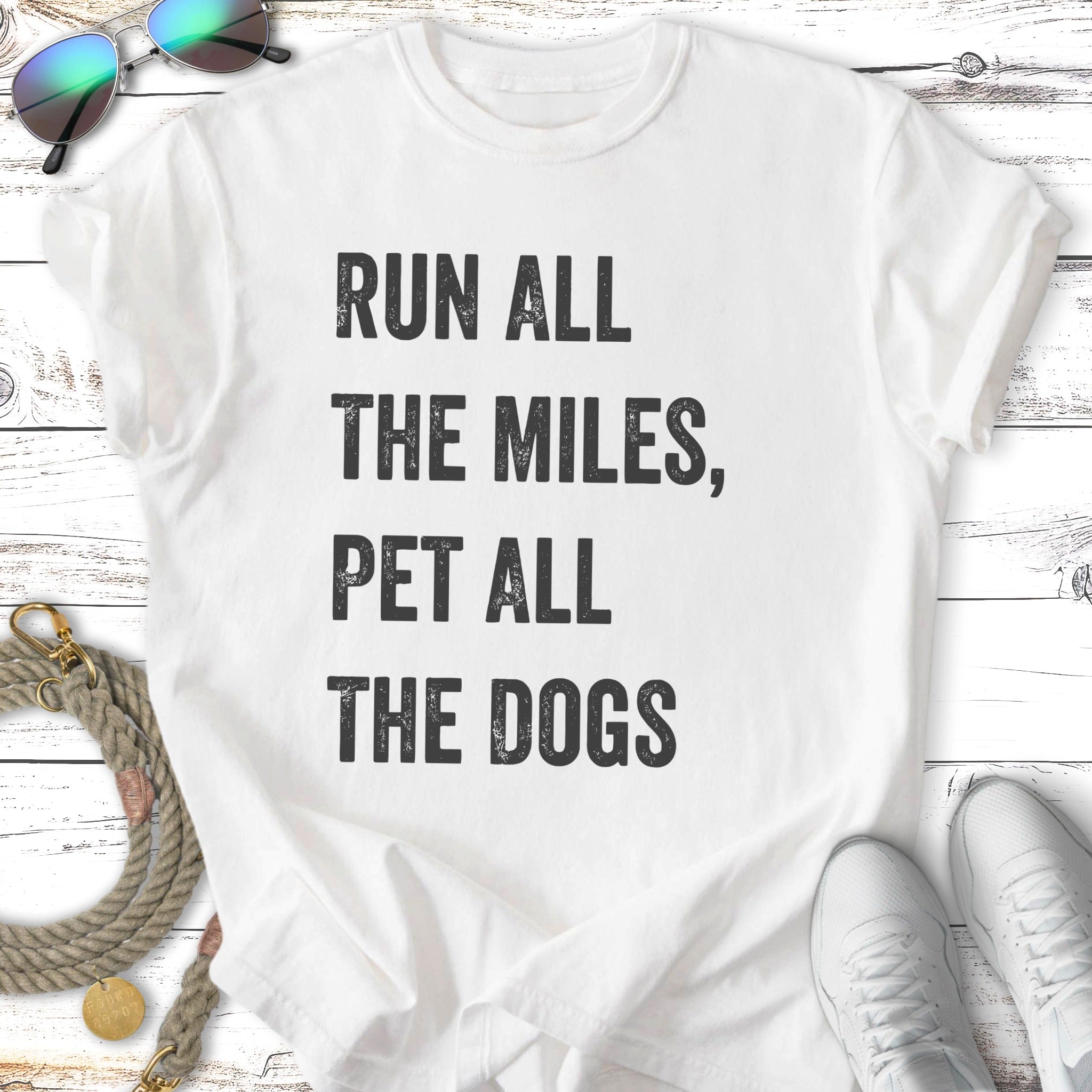 White t-shirt with "Run All The Miles, Pet All The Dogs" text.