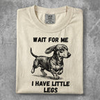 Cream t-shirt with a dachshund illustration and "WAIT FOR ME I HAVE LITTLE LEGS" text.