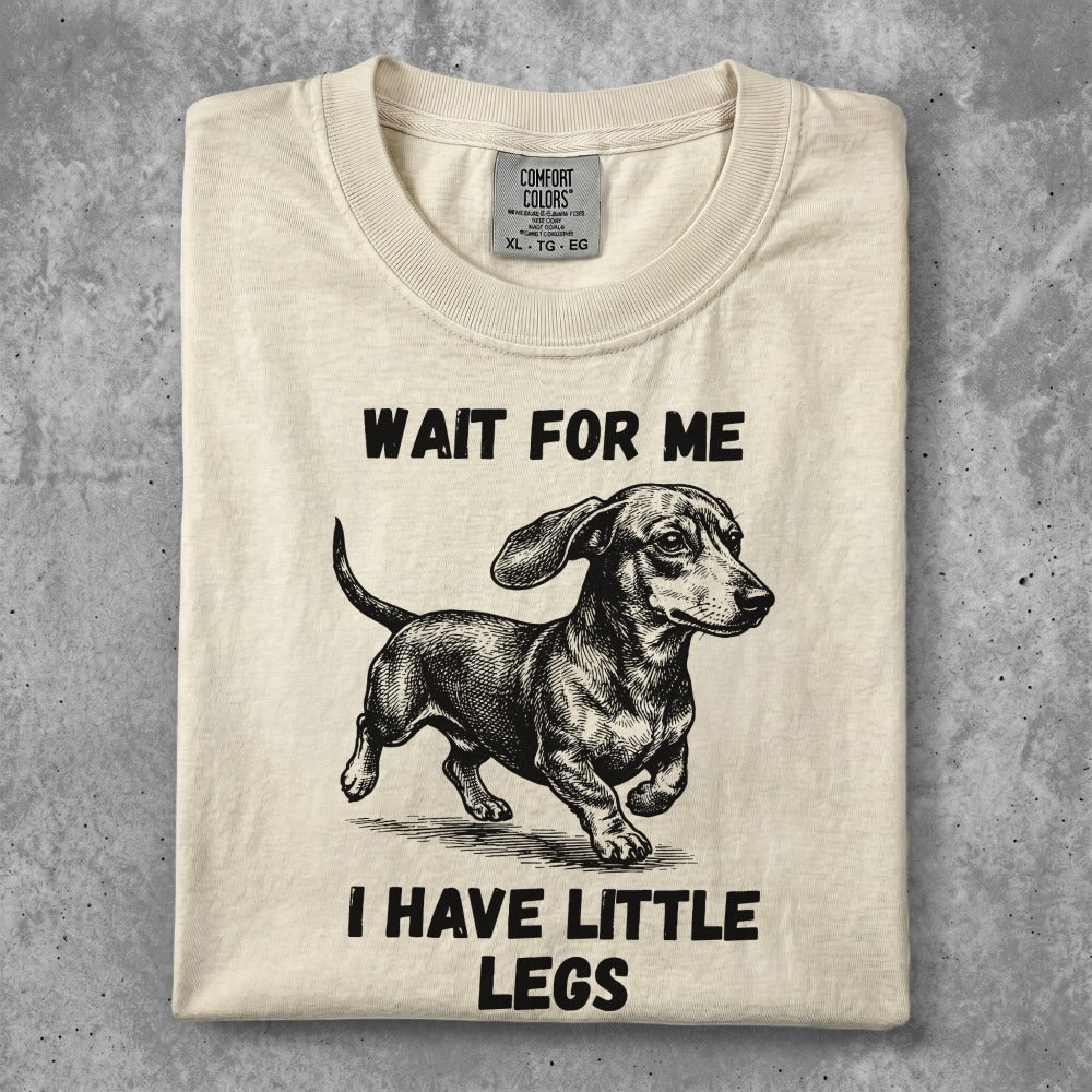 Cream t-shirt with a dachshund illustration and "WAIT FOR ME I HAVE LITTLE LEGS" text.