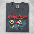 Two golden retrievers wearing life vests swim in a lake with "It's Lake time" text.