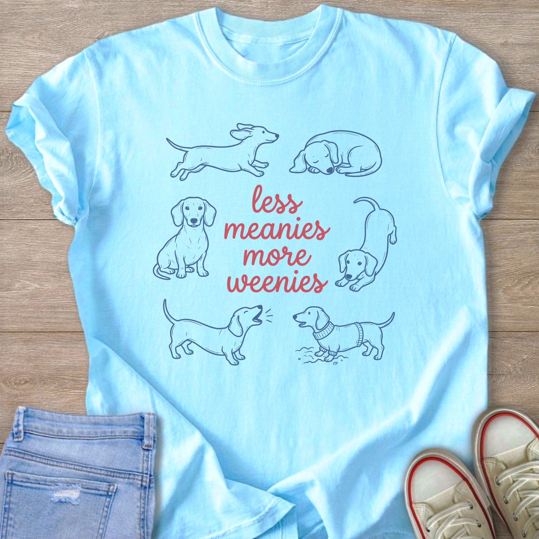 Light blue t-shirt with cartoon dachshunds and text reading "less meanies more weenies."
