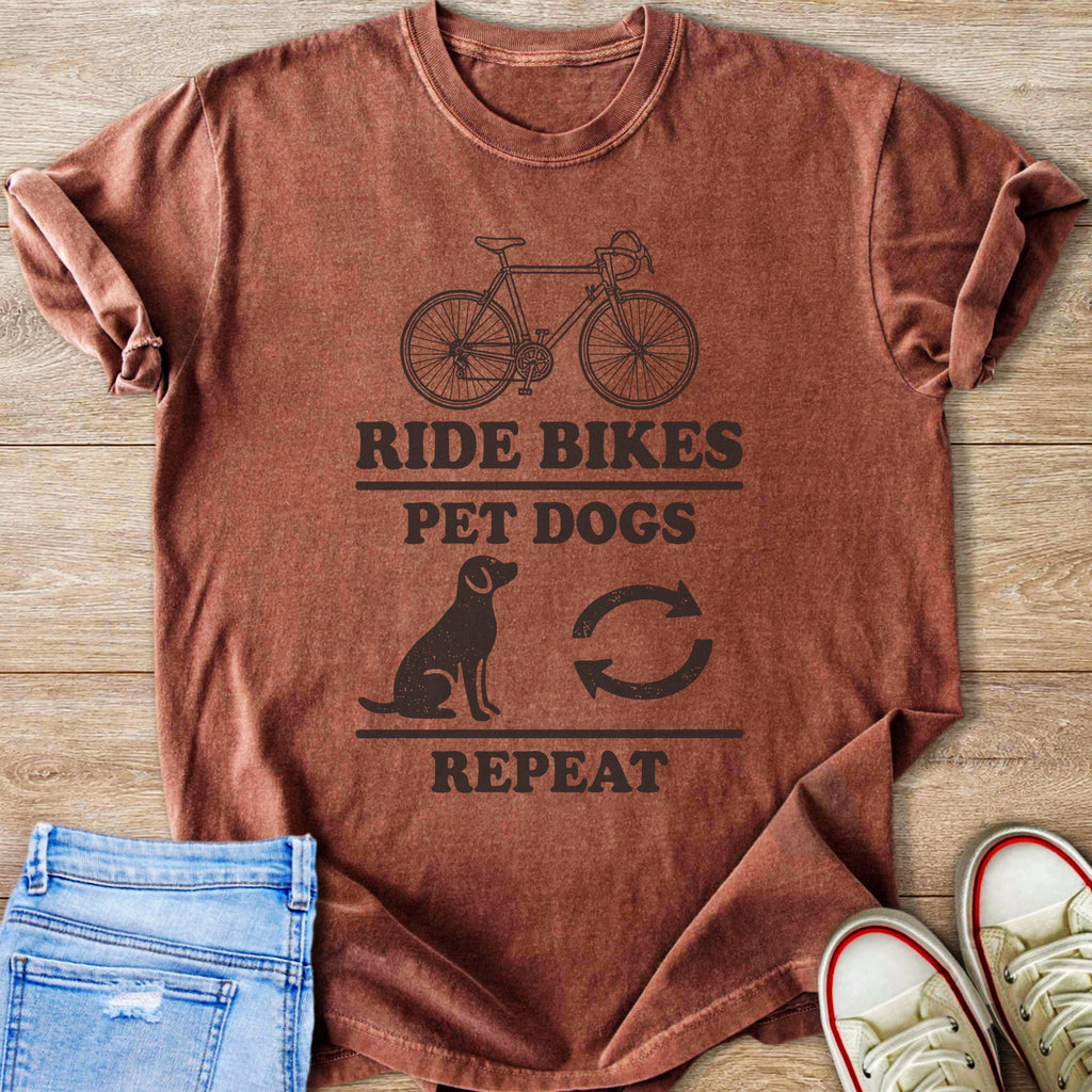 Brown t-shirt with graphic text "Ride Bikes Pet Dogs Repeat" and line art.