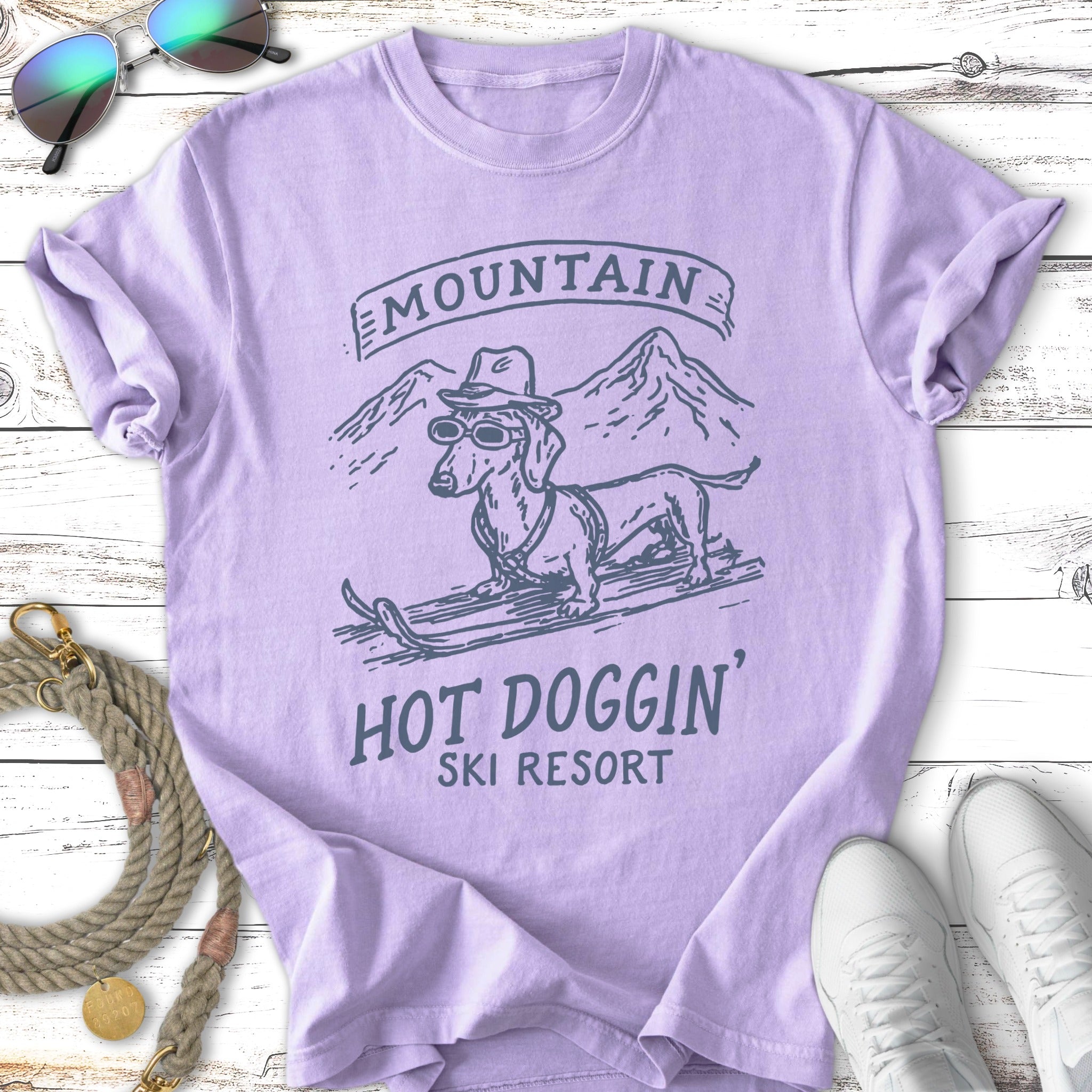 Dachshund in sunglasses on skis with "MOUNTAIN HOT DOGGIN' SKI RESORT" text.