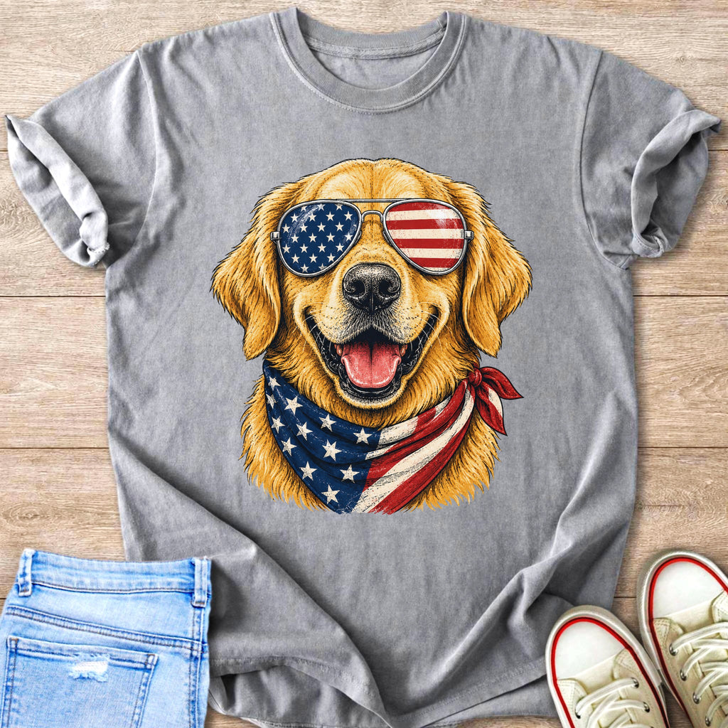 Golden retriever wearing American flag sunglasses and bandana on gray t-shirt.