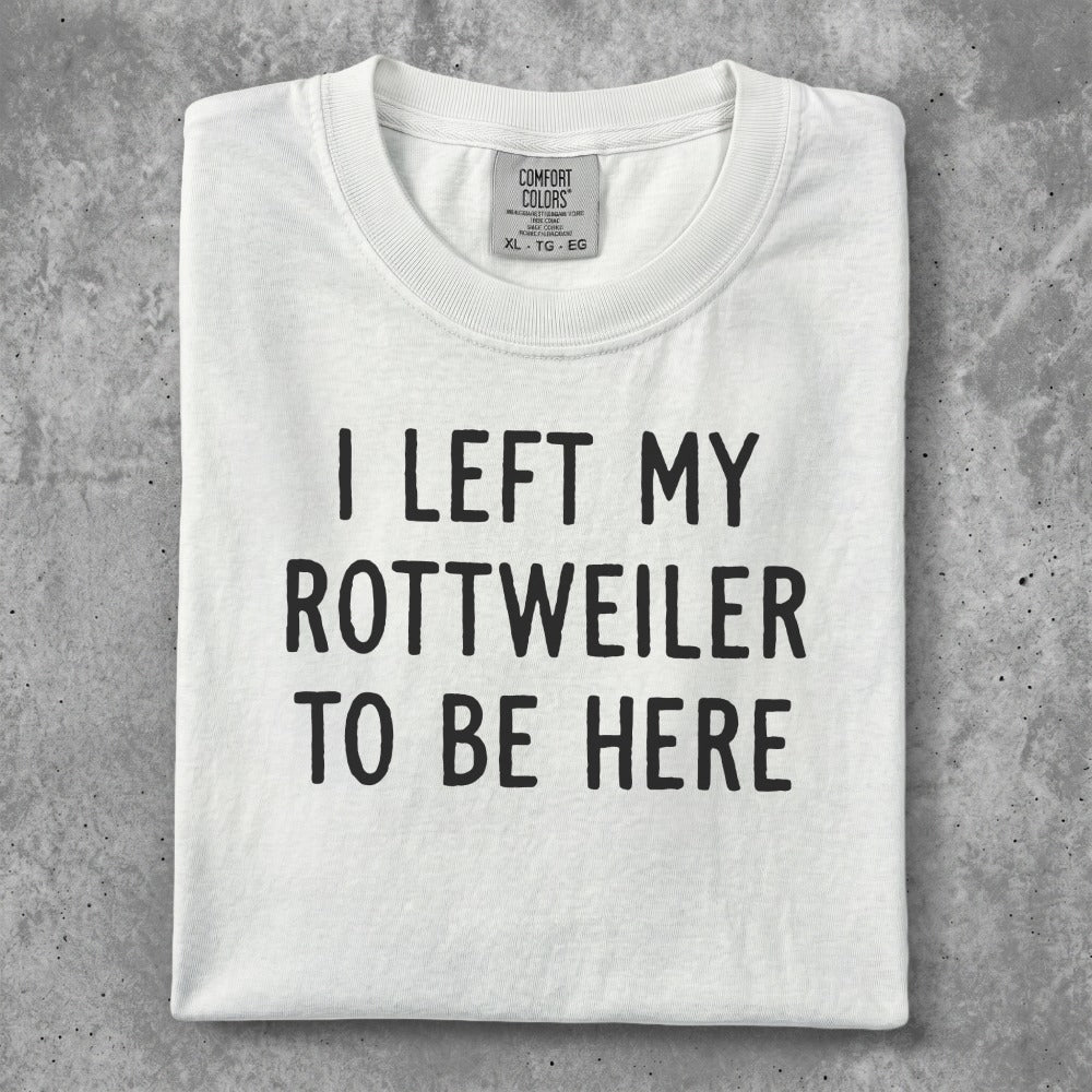 White t-shirt with "I LEFT MY ROTTWEILER TO BE HERE" in black text.