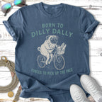 Pug riding bicycle with baguette, "Born to Dilly Dally" shirt.