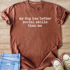 Brown t-shirt with white text "my dog has better social skills than me".