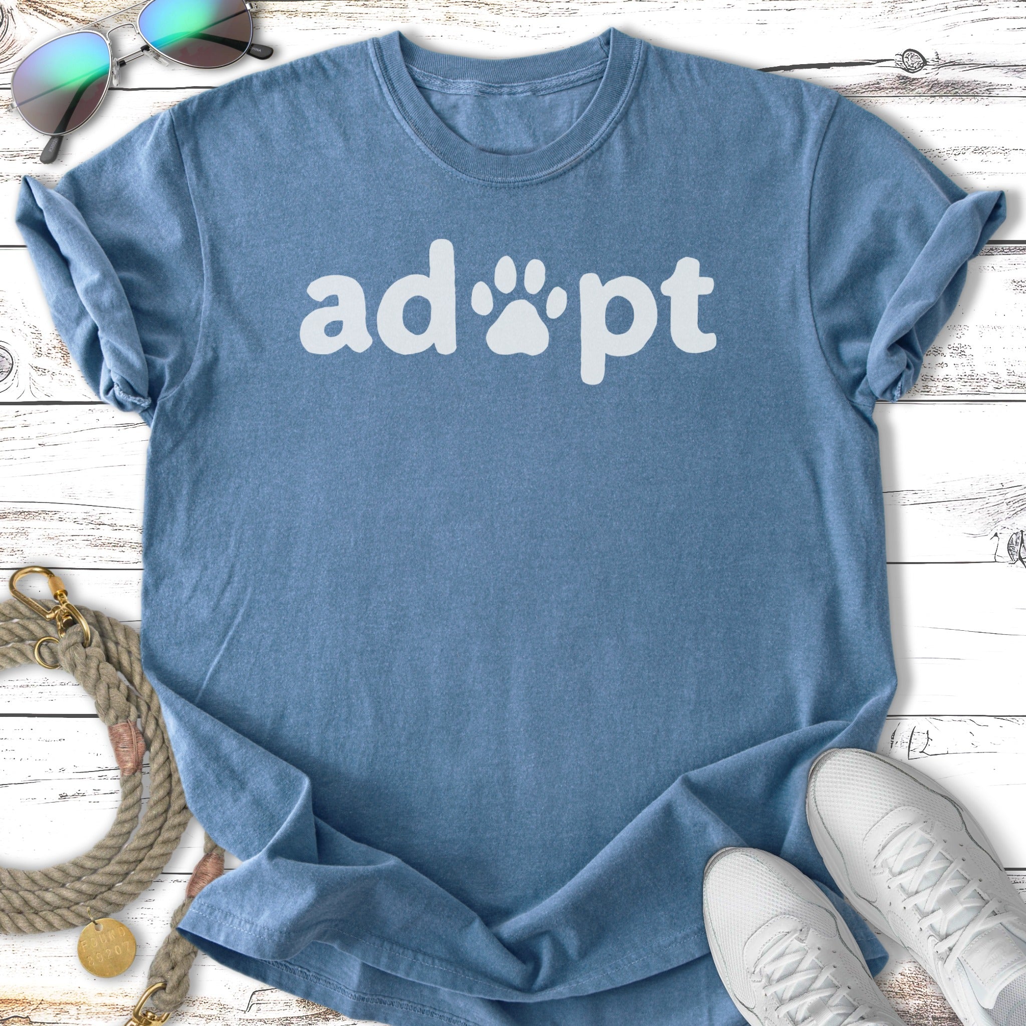 Blue t-shirt with "adopt" and paw print text.
