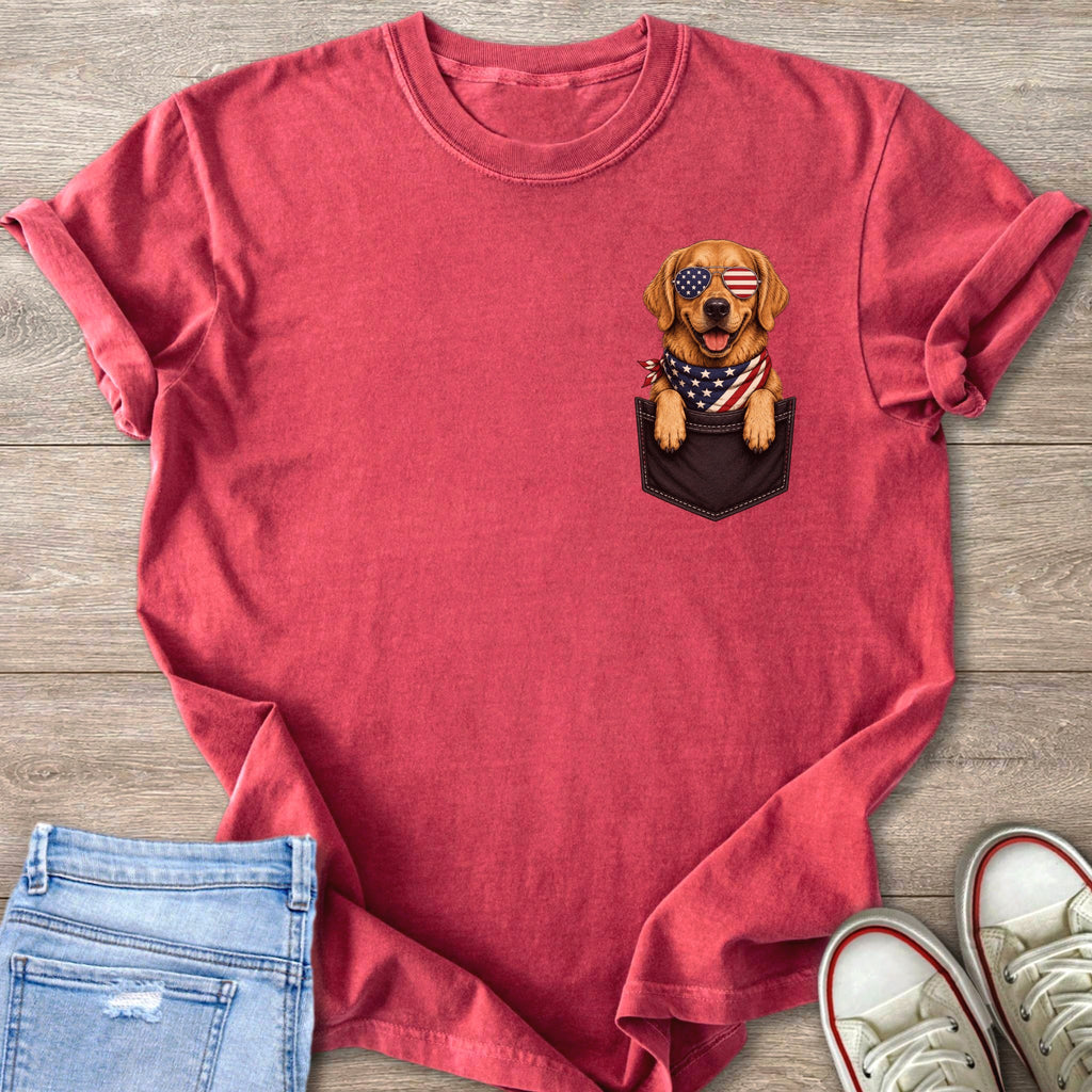 Golden retriever wearing American flag bandana and sunglasses peeking from shirt pocket.