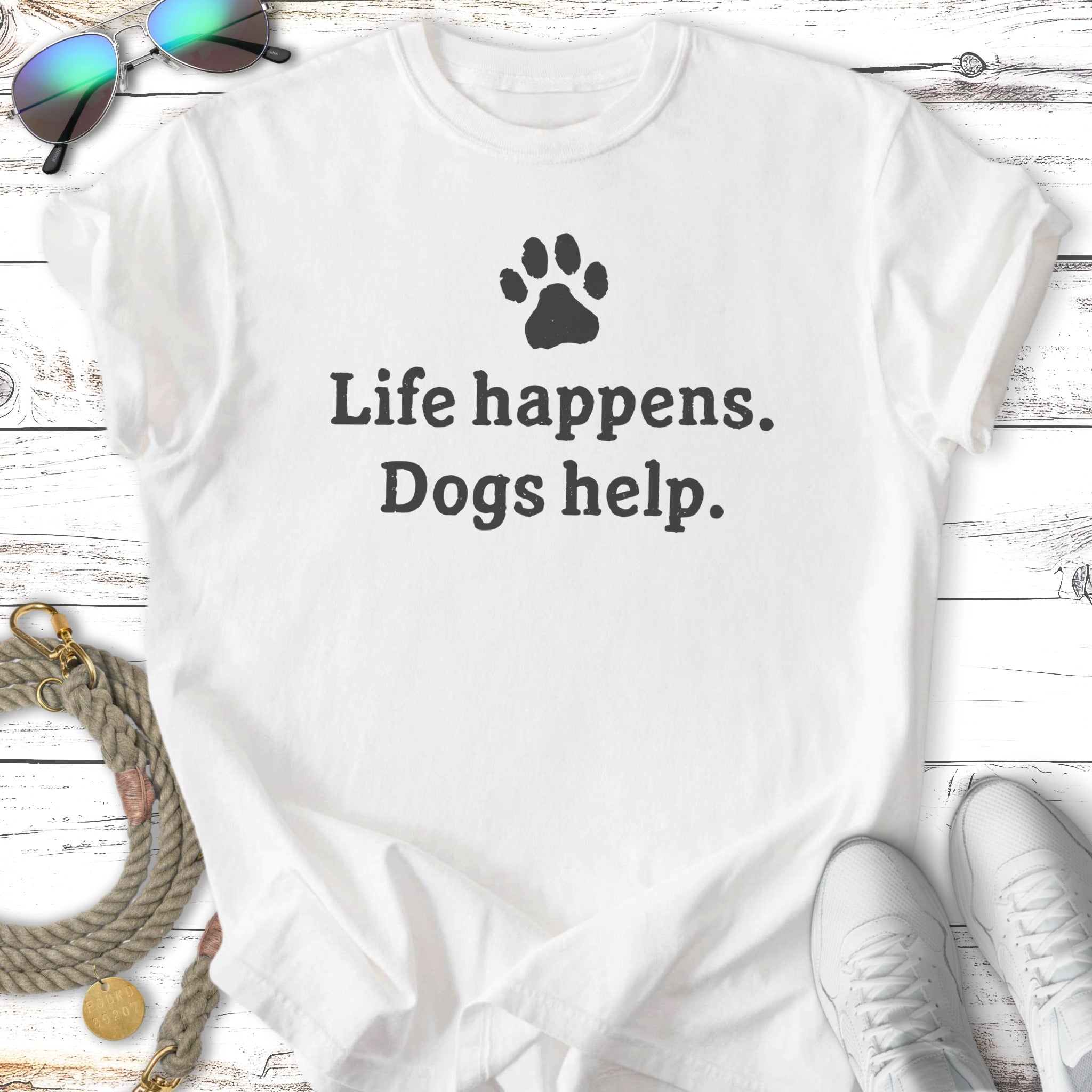 White t-shirt with "Life happens. Dogs help." and a paw print graphic.