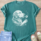 Teal t-shirt with white line drawing of a golden retriever blowing dandelion seeds.