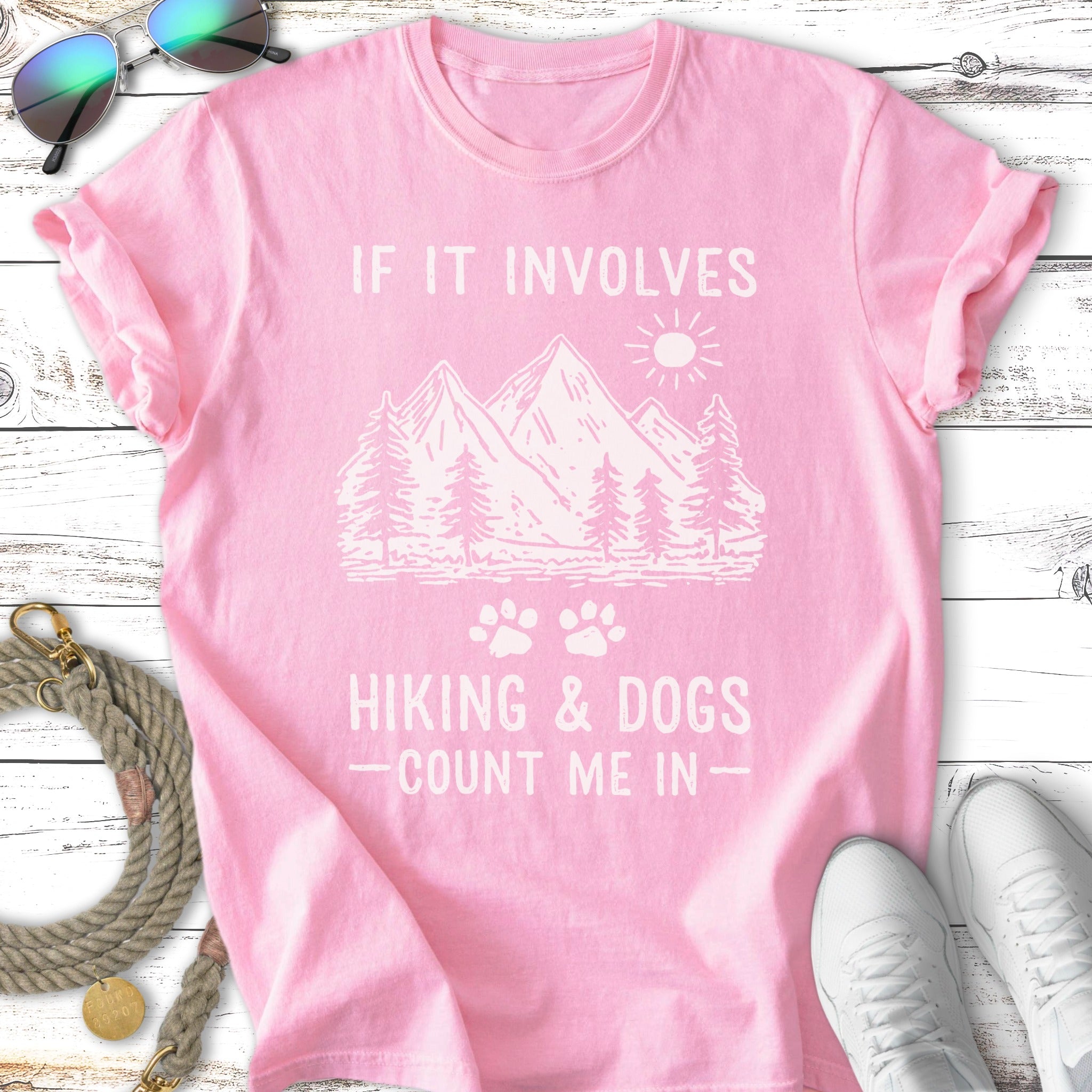 Pink t-shirt with "If It Involves Hiking & Dogs, Count Me In" text and mountain graphic.