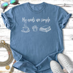 Blue t-shirt with "My needs are simple" text, coffee cup, paw print, and book icons.