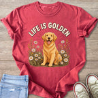 Golden Retriever dog with "LIFE IS GOLDEN" text in floral setting on a red t-shirt.